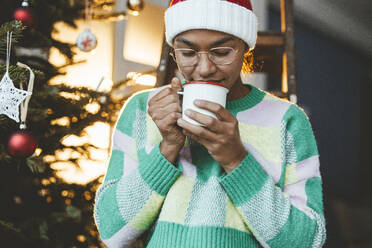 Young woman smelling coffee standing at home - JOSEF23811