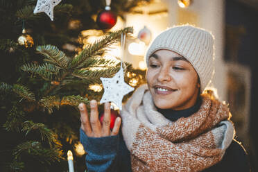 Junge Frau betrachtet die Dekoration des Weihnachtsbaums - JOSEF23830