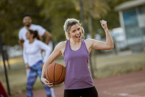 Portrait of fitness young woman with basketball ball playing game outdoor - INGF13003