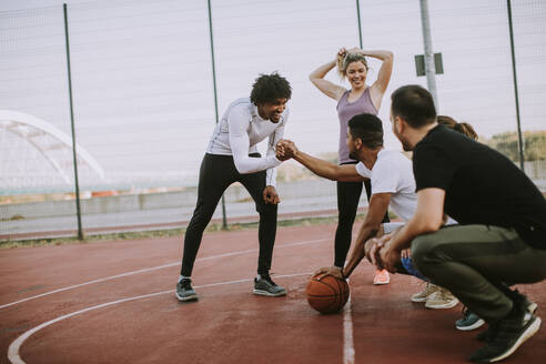 Group of multiethnic young people playing basketball on court - INGF13005