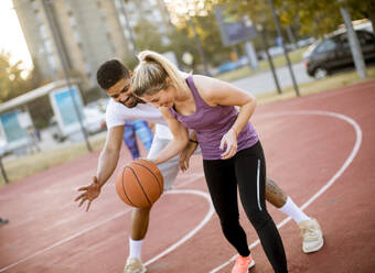 Group of young multiethnic young people playing basketball on court - INGF13006