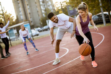 Group of multiethnic young people playing basketball on court - INGF13007