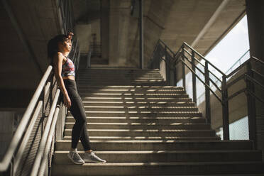 Portrait of pretty young female runner resting on stairs - INGF13011