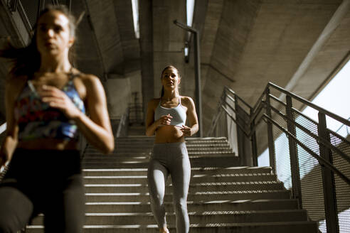 Two young woman workout down stairs in urban environment - INGF13013