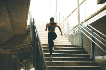 Young woman running alone up stairs outdoor - INGF13017