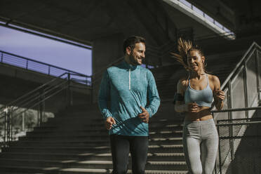 Young couple running in urban enviroment at sunny day - INGF13023