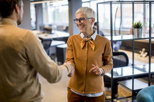 Young business man and senior business woman shaking hands in the modern office - INGF13069