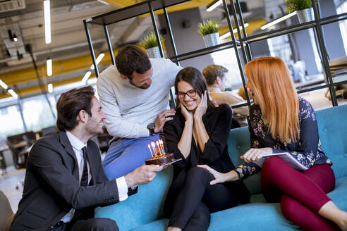 Birthday party for the young female colleague in the modern office with the small cake - INGF13080