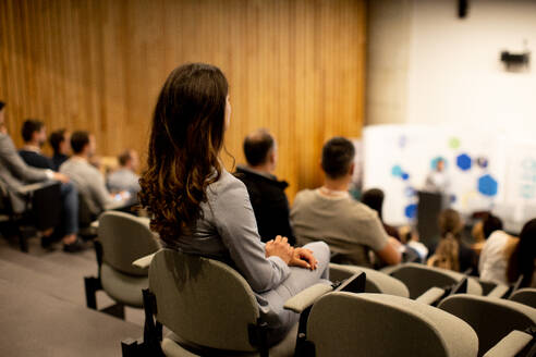 Pretty young woman sitting in audience on conference or workshop - INGF13085