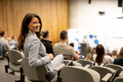 Pretty young woman sitting in audience on conference or workshop - INGF13086