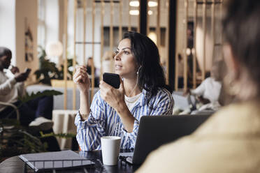 Businesswoman talking on smart phone while sitting at coworking office - MASF43000