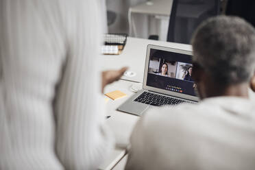 Business colleagues on video call through laptop with team at office - MASF43035