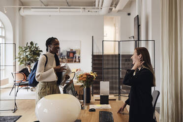 Happy female business professionals greeting each other at coworking office - MASF43043