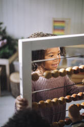 Schoolgirl using abacus in classroom at kindergarten - MASF43060