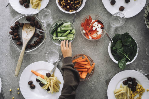 Directly above view of boy taking pickled cucumber from bowl during lunch time at kindergarten - MASF43089