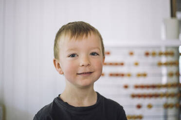 Portrait of smiling boy with blond hair in classroom at kindergarten - MASF43116