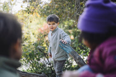 Portrait of boy holding tree branch at park - MASF43133