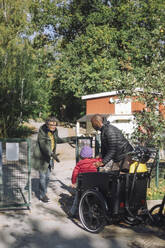 Female teacher assisting children while entering at kindergarten - MASF43136