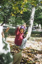 Playful girl hanging on rope while playing at park - MASF43137