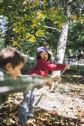 Girl leaning on rope while playing with boy at park - MASF43138