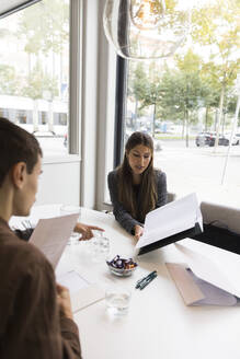 Female real estate agent explaining floor plan to customers in office - MASF43151