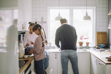 Siblings preparing food with father working in kitchen at home - MASF43192