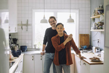 Portrait of smiling multiracial gay couple standing in kitchen at home - MASF43196