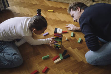 High angle view of father and daughter playing toy blocks on floor at home - MASF43204