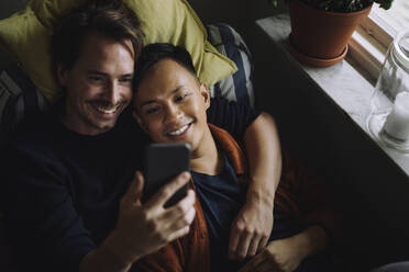 High angle view of multiracial gay couple using smart phone at home - MASF43219