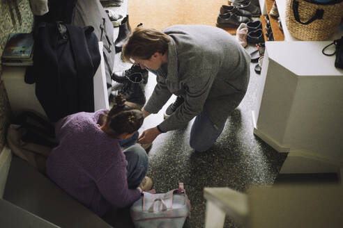 High angle view of father tying shoelace of daughter while leaving for school - MASF43226