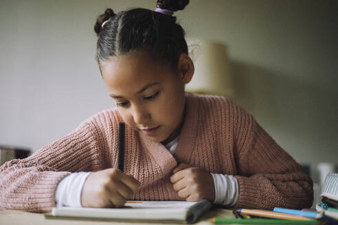 Girl with pigtails coloring on book at home - MASF43231