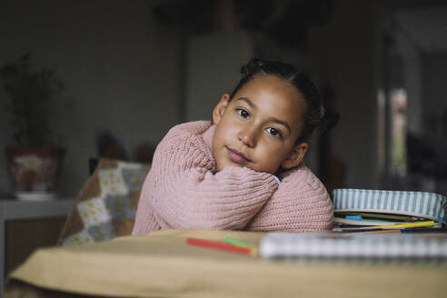 Portrait of girl resting head on arms at table in home - MASF43235