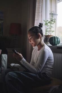 Girl using smart phone while sitting at home - MASF43253
