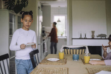 Girl setting up table for breakfast at home - MASF43261