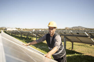 Young male maintenance engineer repairing solar panels at power station - MASF43294