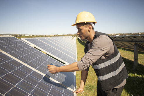 Young male engineer photographing solar panels through smart phone at power station - MASF43304