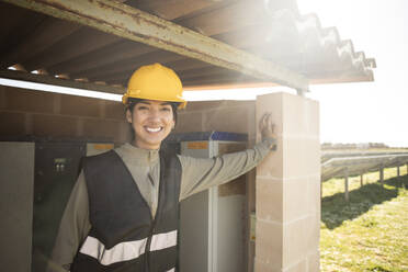 Portrait of smiling female engineer leaning on pillar of control room at power station - MASF43322