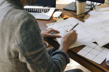 Midsection of male architect drawing blueprint on paper at desk in home office - MASF43344