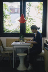 Full length side view of mature female architect using laptop at desk in home office - MASF43370