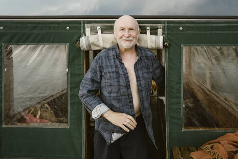 Portrait of senior man standing at houseboat entrance - MASF43394