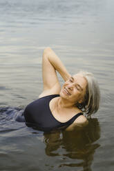 Happy senior woman swimming in river - MASF43420