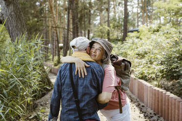 Happy senior woman hugging man while hiking in forest - MASF43425