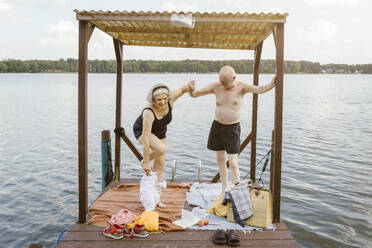 Full length of senior man helping woman in removing shorts at gazebo - MASF43431