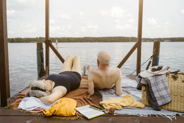 Senior couple lying together on gazebo over river - MASF43440