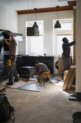 Multiracial male and female carpenters working in kitchen at home - MASF43465