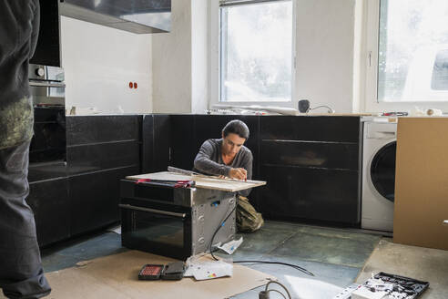 Serious female carpenter marking on plank in kitchen at home - MASF43479