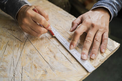 Cropped hands of female carpenter marking on plank with pencil - MASF43481