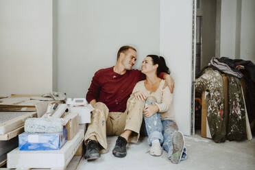 Romantic couple sitting together in room while renovating home - MASF43520