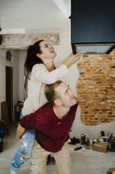 Happy couple fixing lighting equipment while renovating home - MASF43522