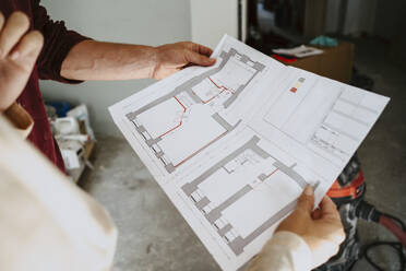 Cropped image of couple discussing over blueprint while renovating home - MASF43548